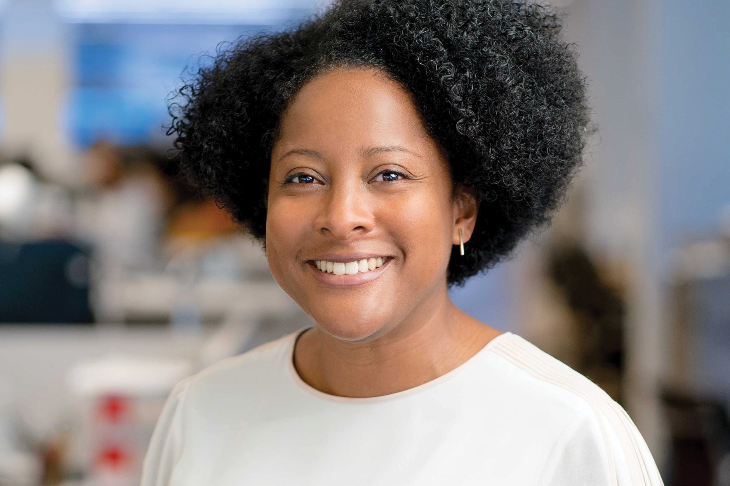 Portrait of Anya Grant wearing a white top and smiling in an indoor environment.